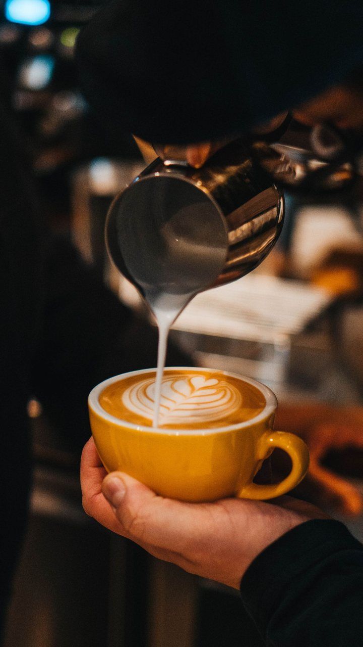 Vertical clip of a barista pouring latte art into a yellow cup