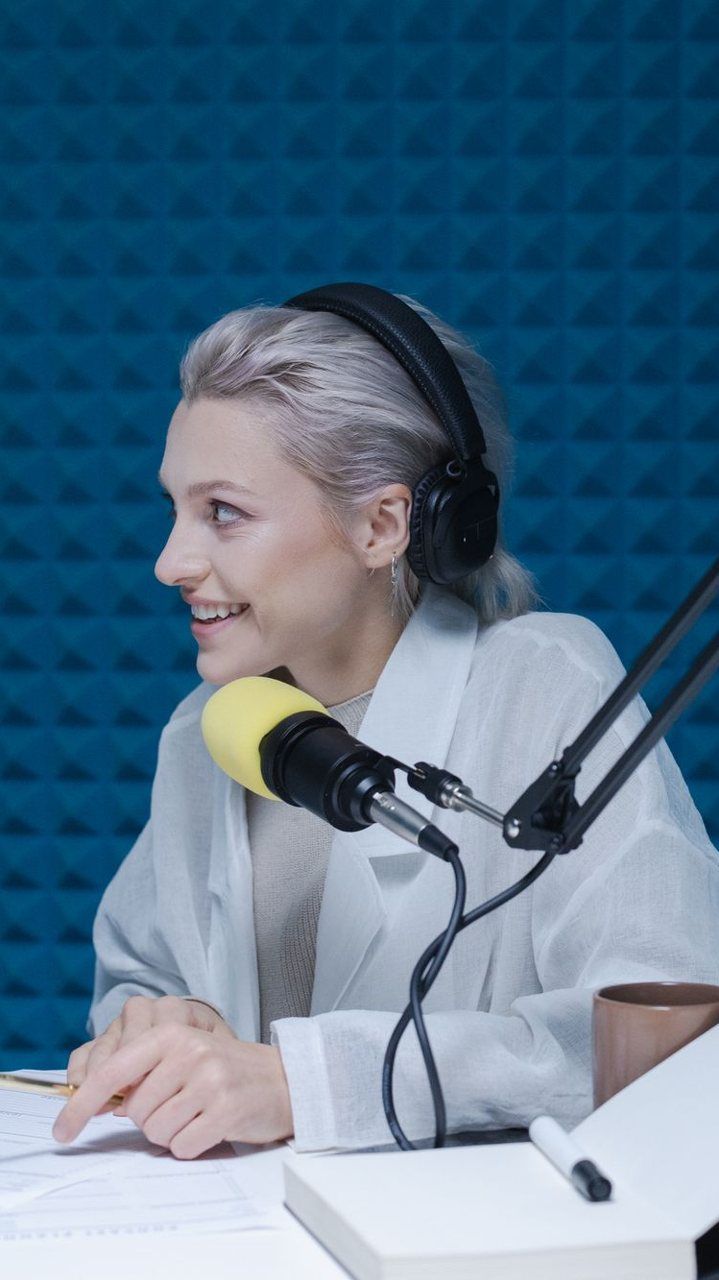 Vertical clip of a podcast host with headphones and a yellow mic